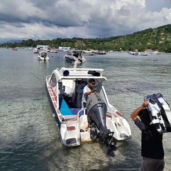A boat with a man steering, another man carrying a large item, and several other boats in the background. 3