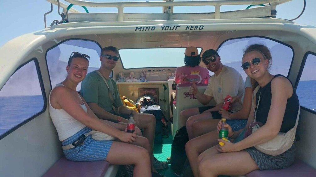 Four people on a boat with a sign that reads 'MIND YOUR HERO' and a view of the sea. 2