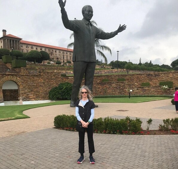 A person standing in front of a large statue with outstretched arms. 5