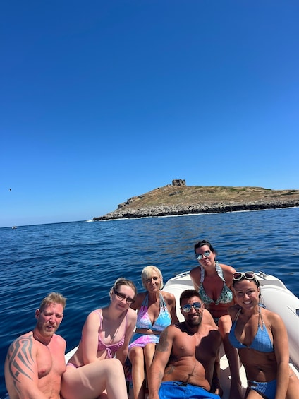 A group of people on a boat near a rocky island with clear blue water. 3