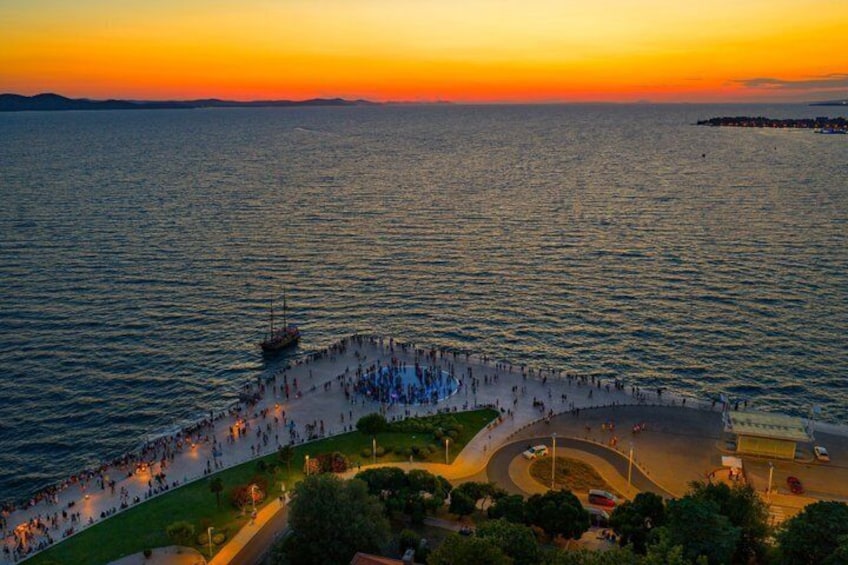 A coastal promenade at sunset with a boat docked on the water. 5