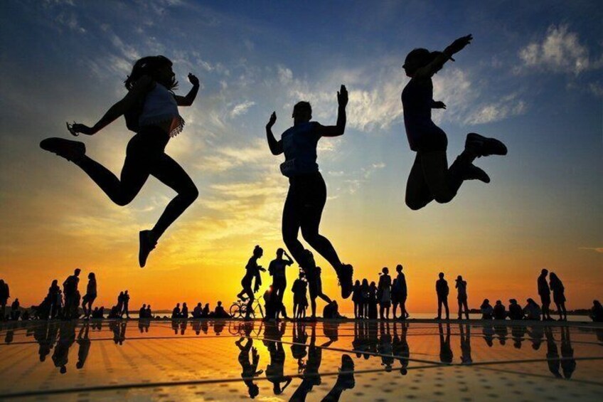 Silhouettes of people jumping against a sunset sky. 1