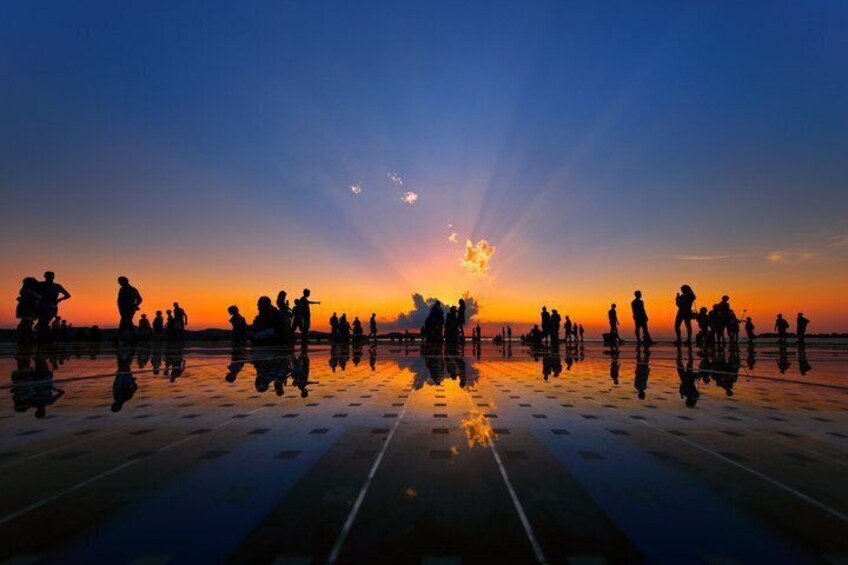 A sunset over a reflective surface with silhouettes of people. 3