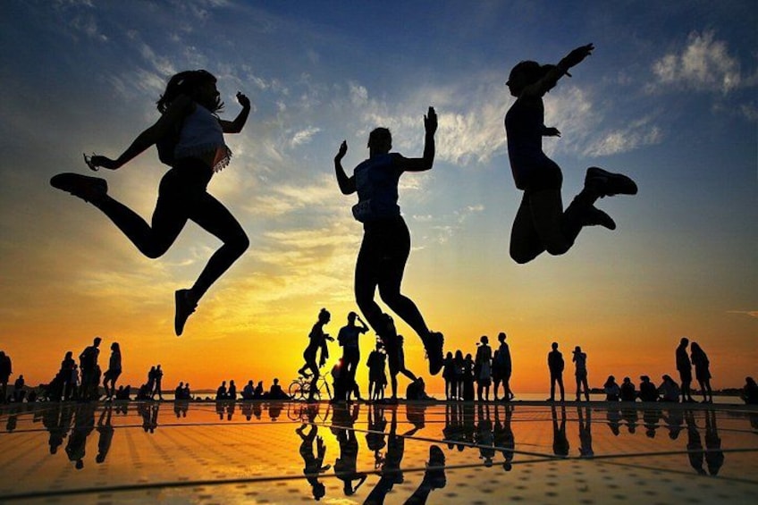 Silhouettes of people jumping against a sunset sky. 1