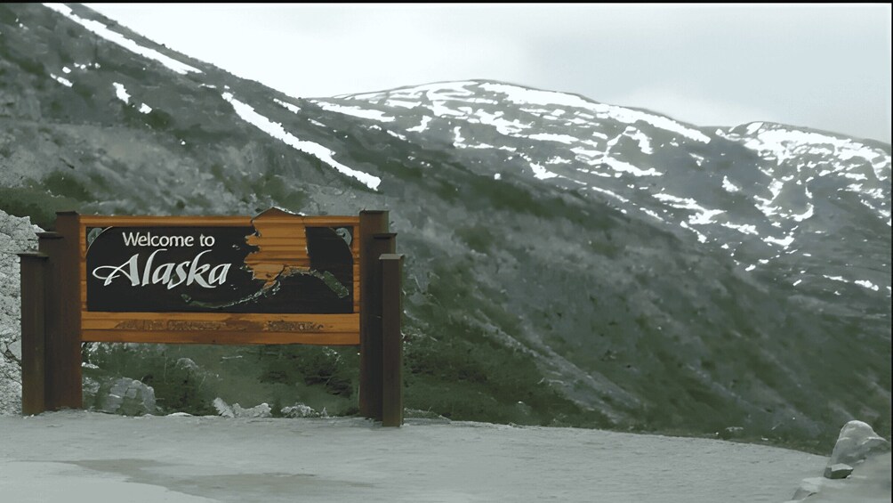 A 'Welcome to Alaska' sign with a mountainous backdrop. 5