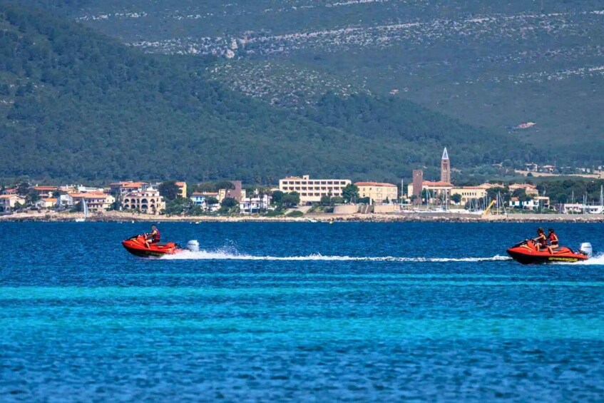 Two red speedboats on a clear blue sea with a coastal town and a hill in the background. 4