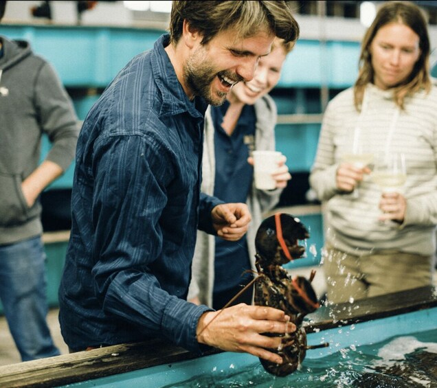 A person holding a lobster at a counter. 2