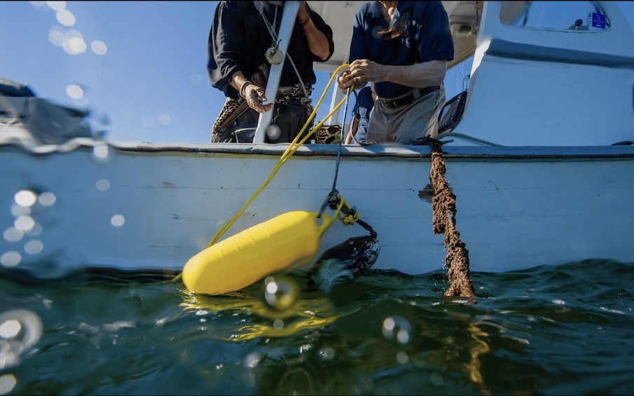 A yellow buoy being lowered into the water from a boat. 3