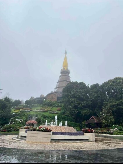 A pagoda with a golden spire, surrounded by a landscaped garden with fountains and flower beds. 2