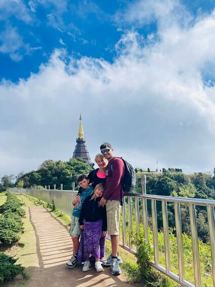 A family posing on a bridge with a pagoda in the background. 1