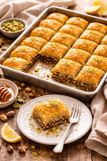 Baklava arranged in a tray and a plate with a fork. 1