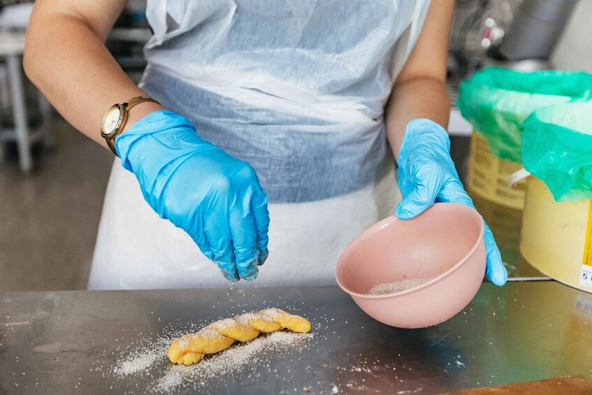 A person wearing blue gloves handling food items on a table. 5
