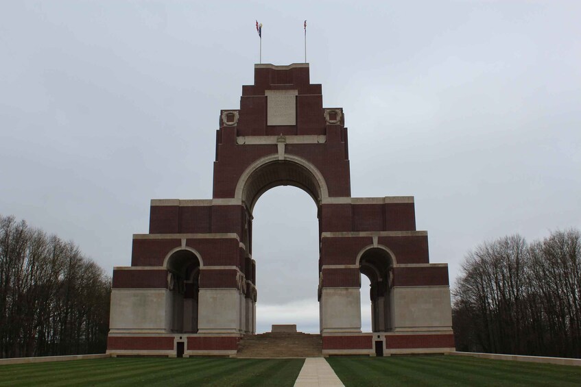 A large brick archway with two flags on top, surrounded by a well-maintained lawn. 1
