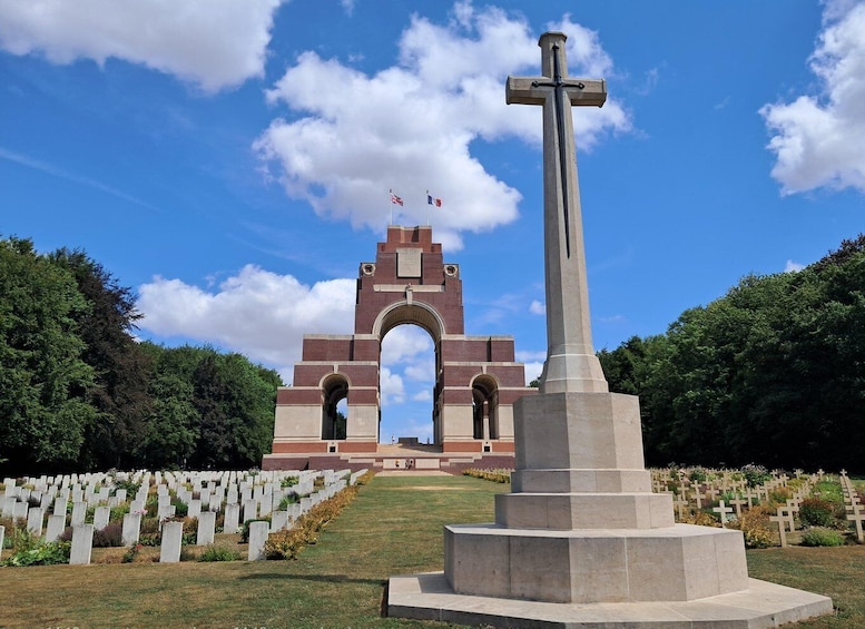 A memorial with a cross, a brick archway, and rows of headstones. 1