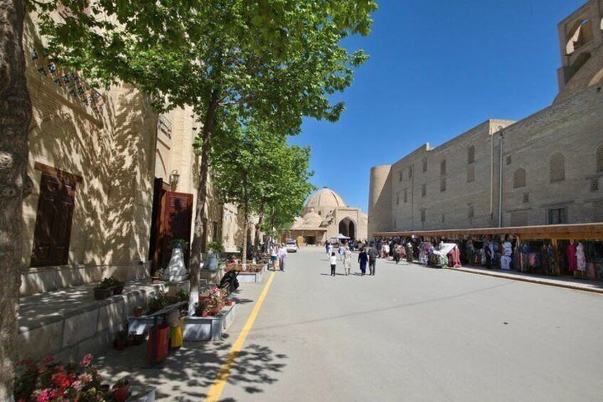 A street lined with trees and buildings, a market with stalls, and a dome structure in the distance. 5