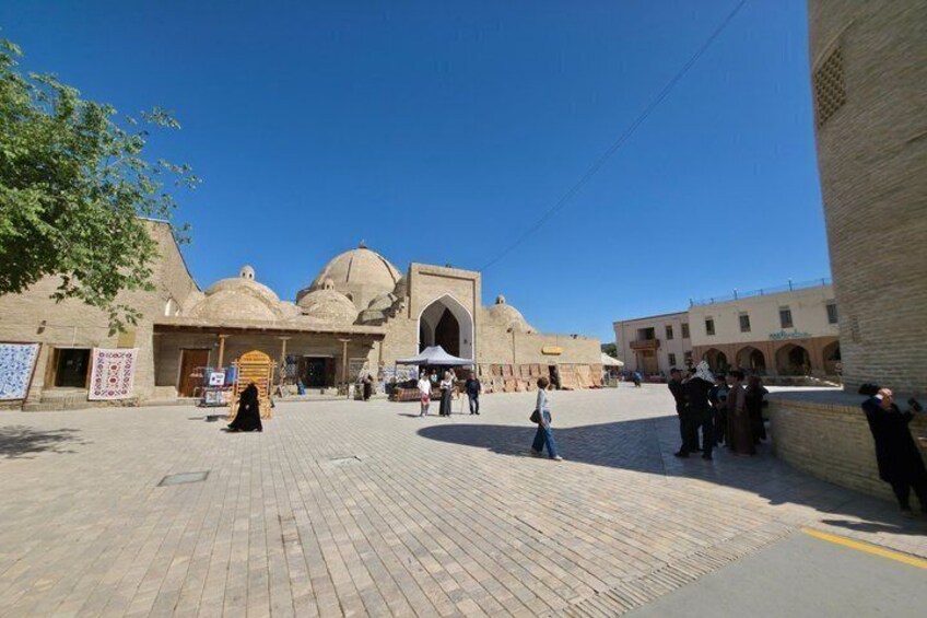A historic square with a prominent mosque featuring domes and arches, surrounded by traditional buildings. 3