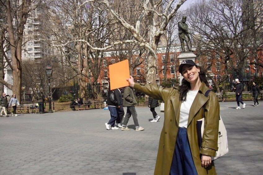 A person in a park with trees and a statue in the background. 2
