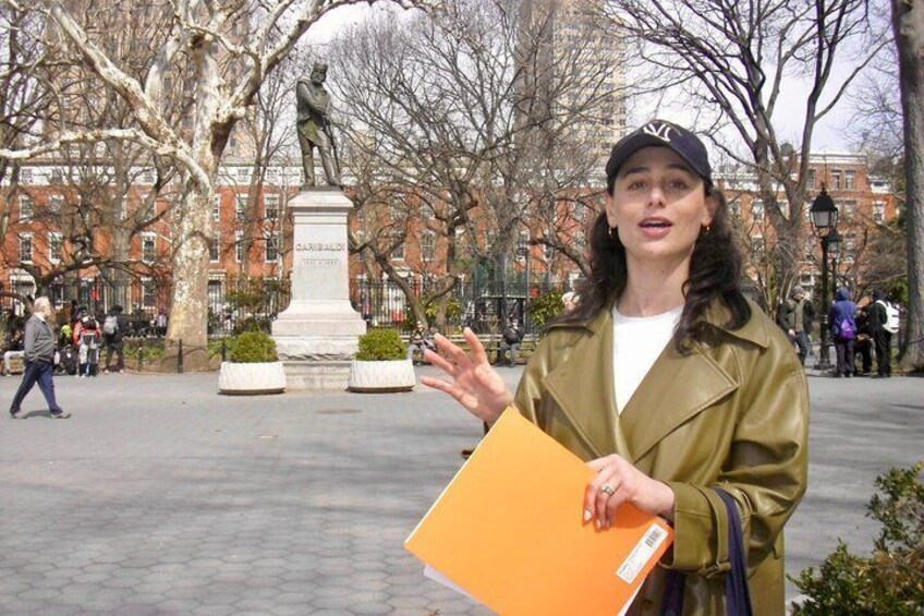 A person holding a folder in a park with a statue and buildings in the background. 4