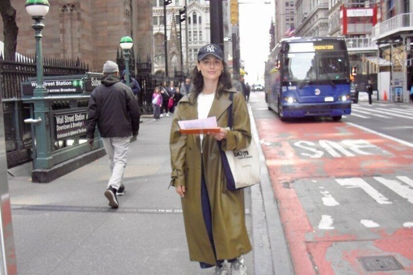 A person standing on a city street with a bus in the background. 5