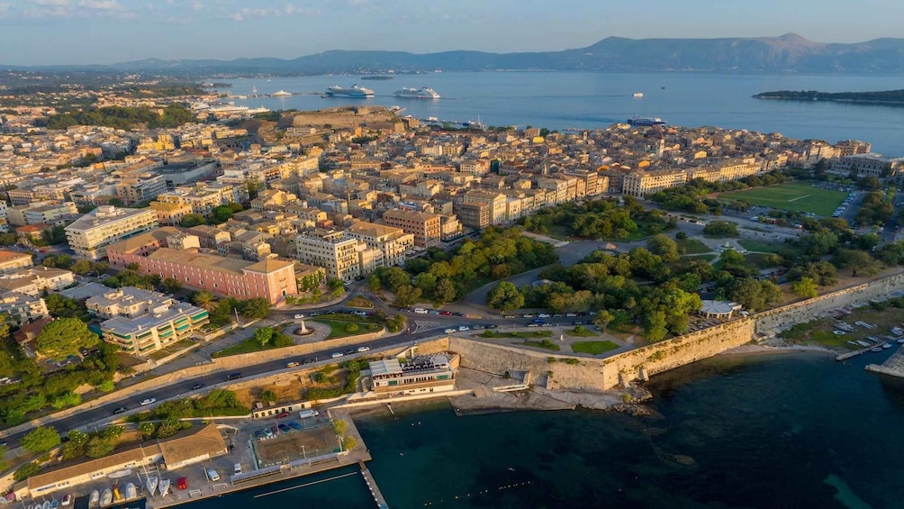 An aerial view of a coastal city with a historic fort, a marina, and a dense urban area with buildings and greenery. 3