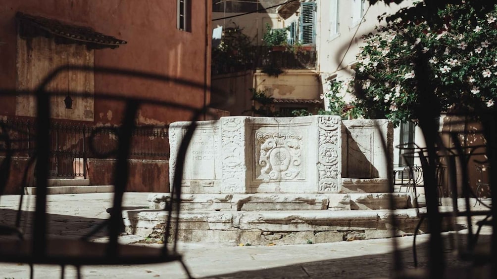 A stone monument with inscriptions, a staircase, and a red building in the background. 4
