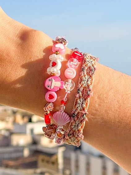 A wrist with multiple bracelets, including a beaded one with a shell charm and a braided one. 5