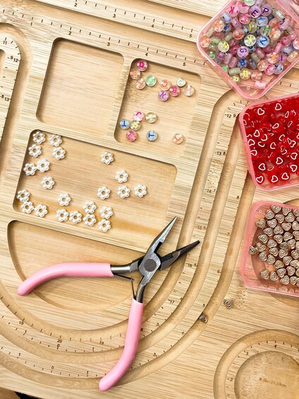 A crafting workspace with beads, a ruler, and pliers. 4