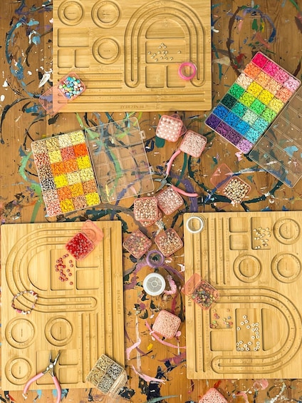 A wooden board with various crafting tools and colorful beads. 2