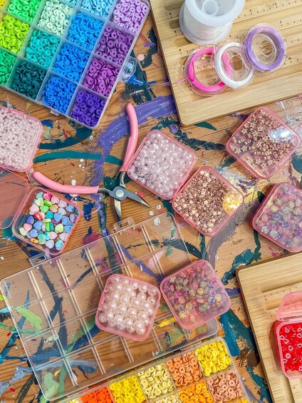 A variety of craft supplies, including beads, sequins, and colorful buttons, spread across a wooden surface. 3