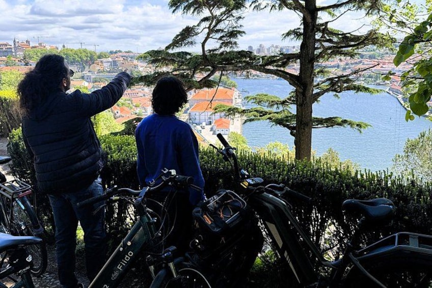 Two people standing by bicycles overlooking a cityscape with a body of water. 2
