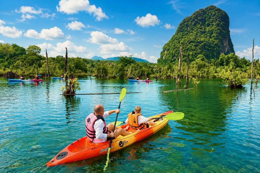Two people kayaking on a calm river surrounded by lush greenery and a prominent mountain in the background. 1