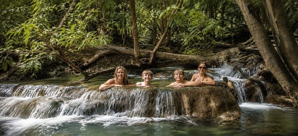 A waterfall with people relaxing on a rock ledge. 5