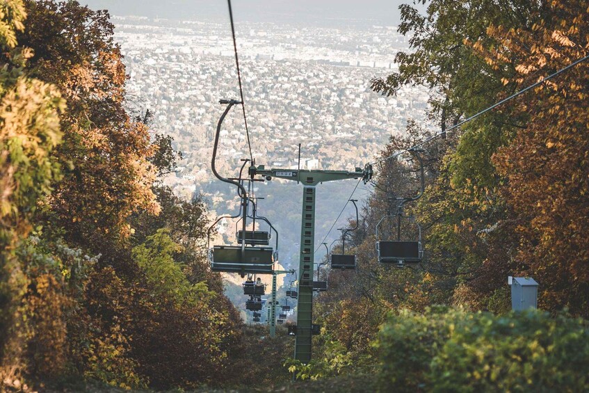 A cable car system amidst autumn foliage with a cityscape in the background. 3