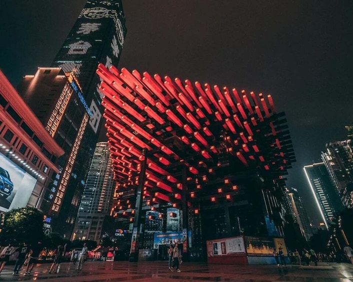 A cityscape at night with a prominent building featuring a red-lit structure. 1