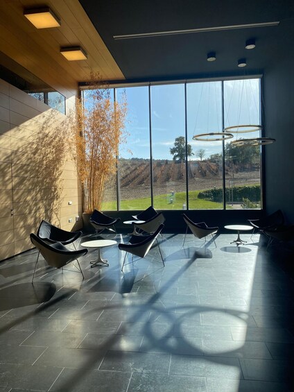 A modern interior with large windows, black chairs, and a view of a hilly landscape. 2