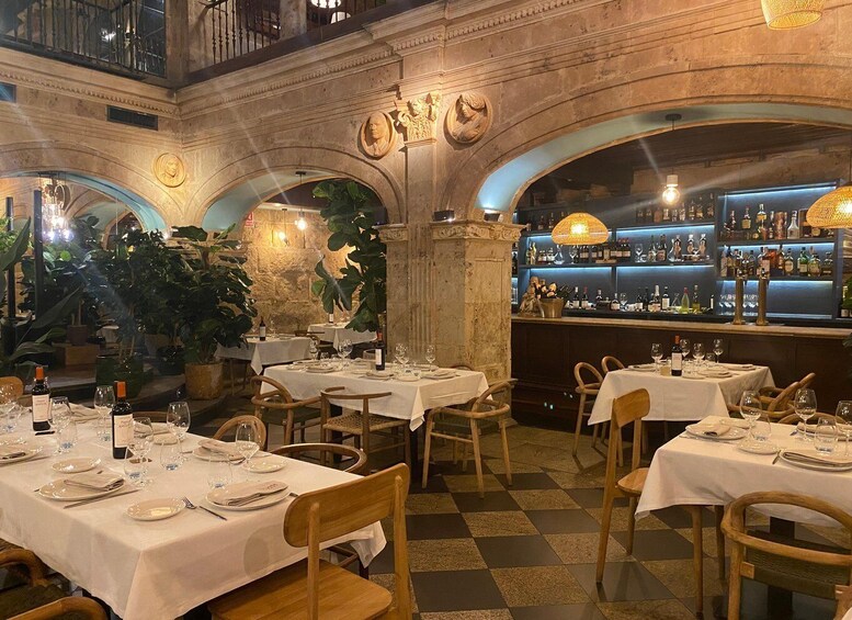 An indoor restaurant with stone arches, wooden tables, and a bar area. 3