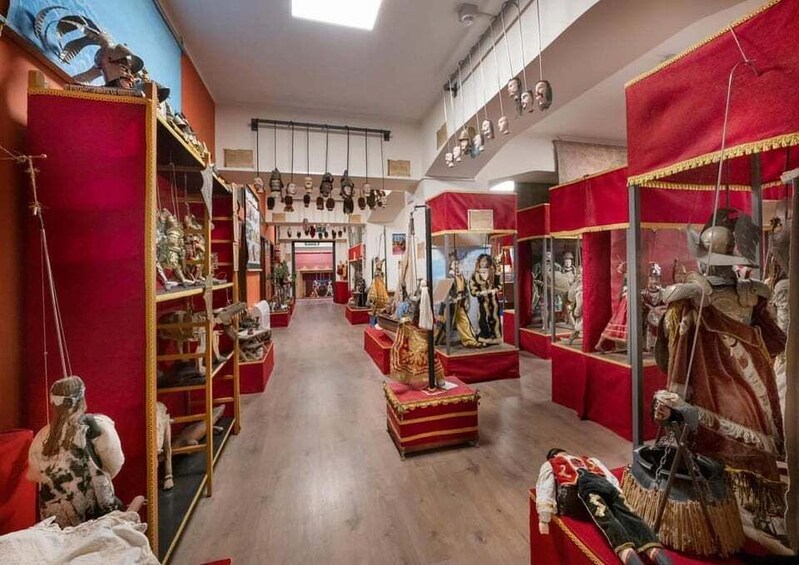 A museum with red and gold displays of historical artifacts and mannequins. 1