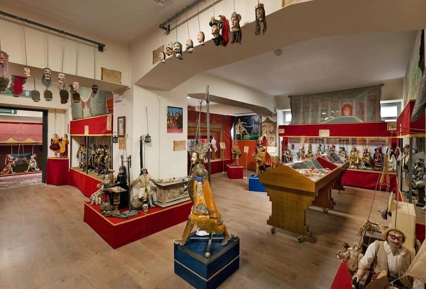 A museum with various historical artifacts, including mannequins and sculptures, displayed on red platforms. 2