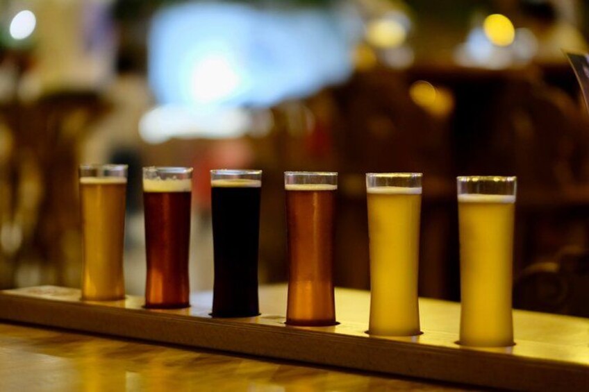 Zes bierglazen op een houten bar. 2