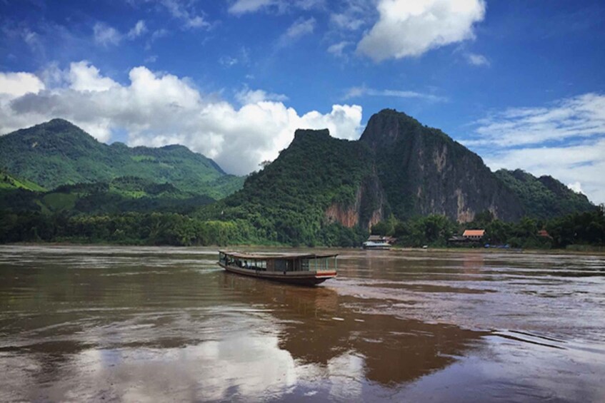 A riverboat on a calm river with mountains in the background. 4