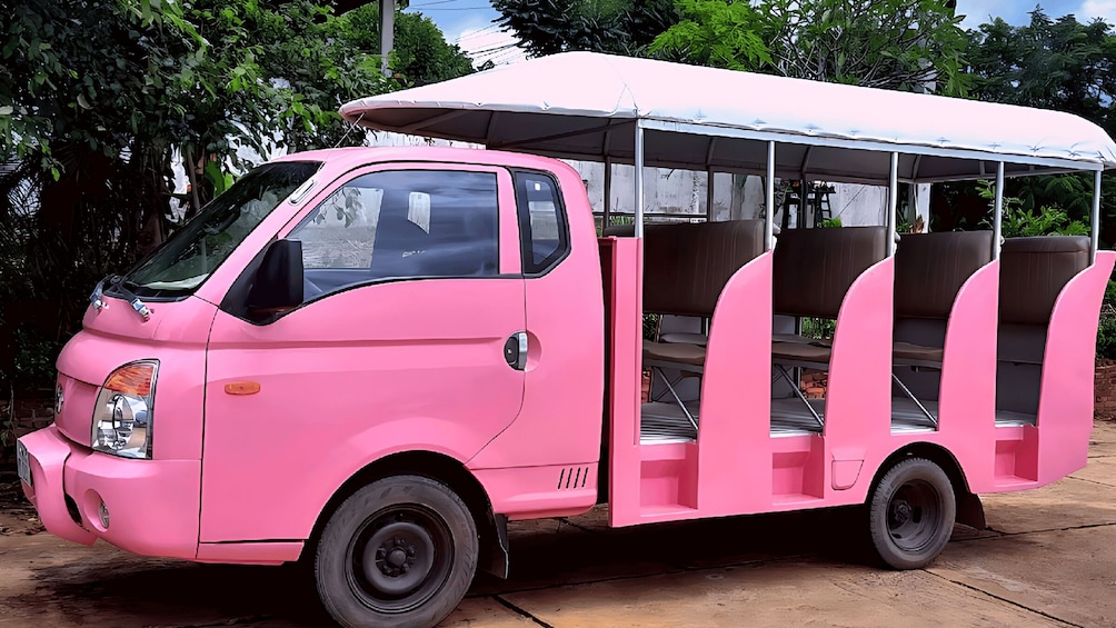 A pink three-wheeled vehicle with a covered seating area. 2