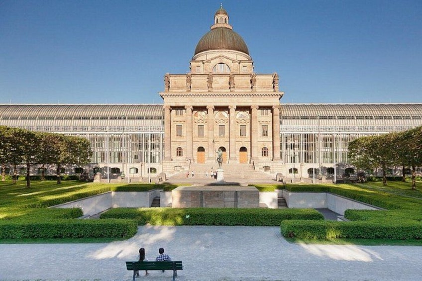 Ein großes Gebäude mit Kuppel, umgeben von einem gepflegten Garten und einem Spiegelteich. 1