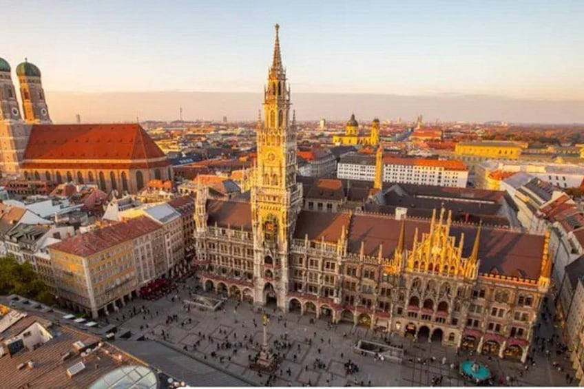 Ein historisches Gebäude mit einem hohen Turm, umgeben von anderen Gebäuden und einem Platz. 2