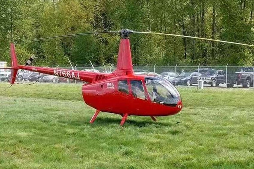 En rød helikopter med registreringsnummer N766AJ parkeret på græs. 4