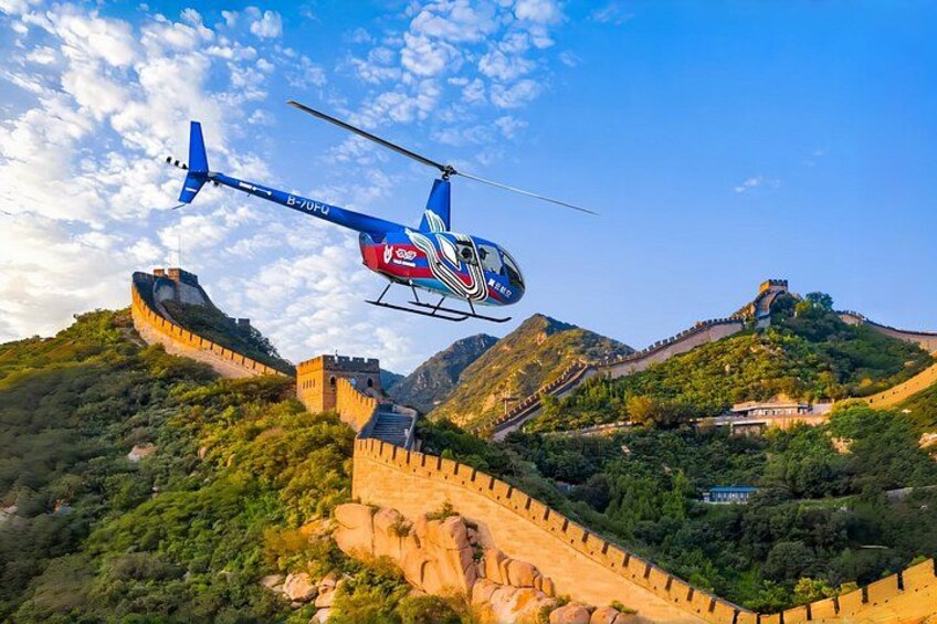 En helikopter flyver over Kina's kinesiske mur med frodige grønne bakker i baggrunden. 1