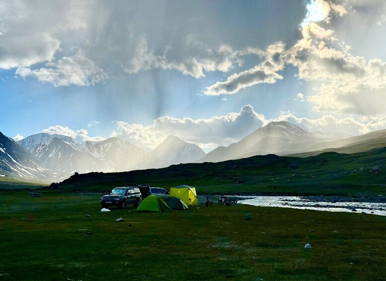 A camping site with tents and a car in a mountainous area with a river. 2