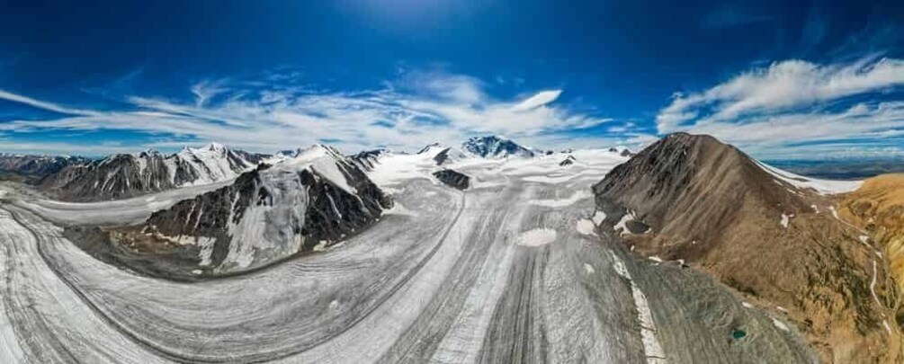 A panoramic view of a glacier with rugged mountains in the background. 4