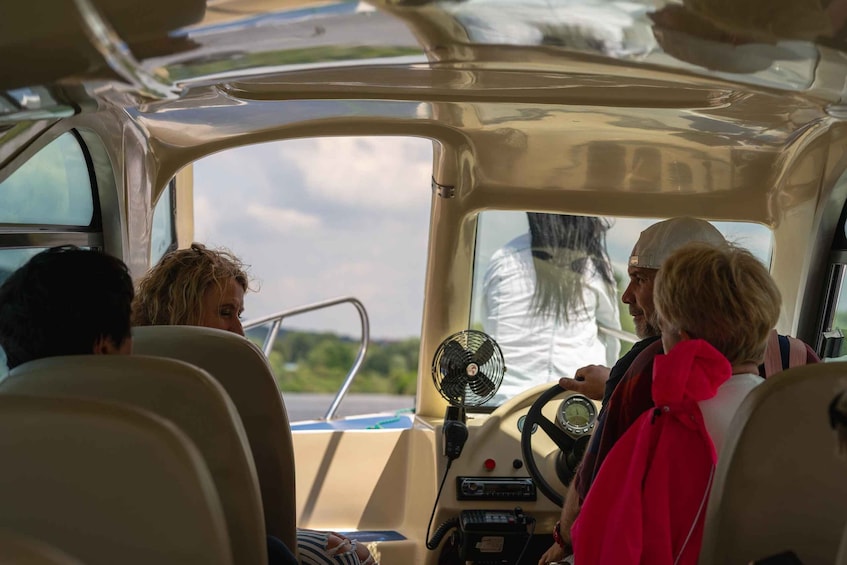 A boat interior with a steering wheel, dashboard, and a fan. 2