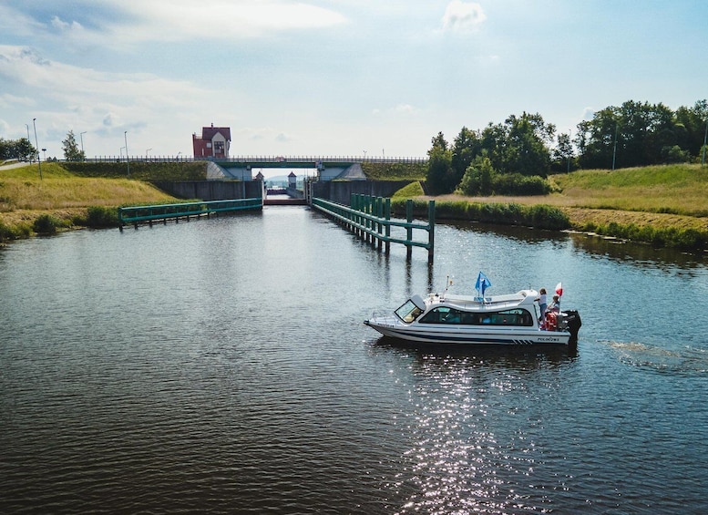 A narrowboat on a canal with a lock ahead, surrounded by greenery and a bridge in the background. 4