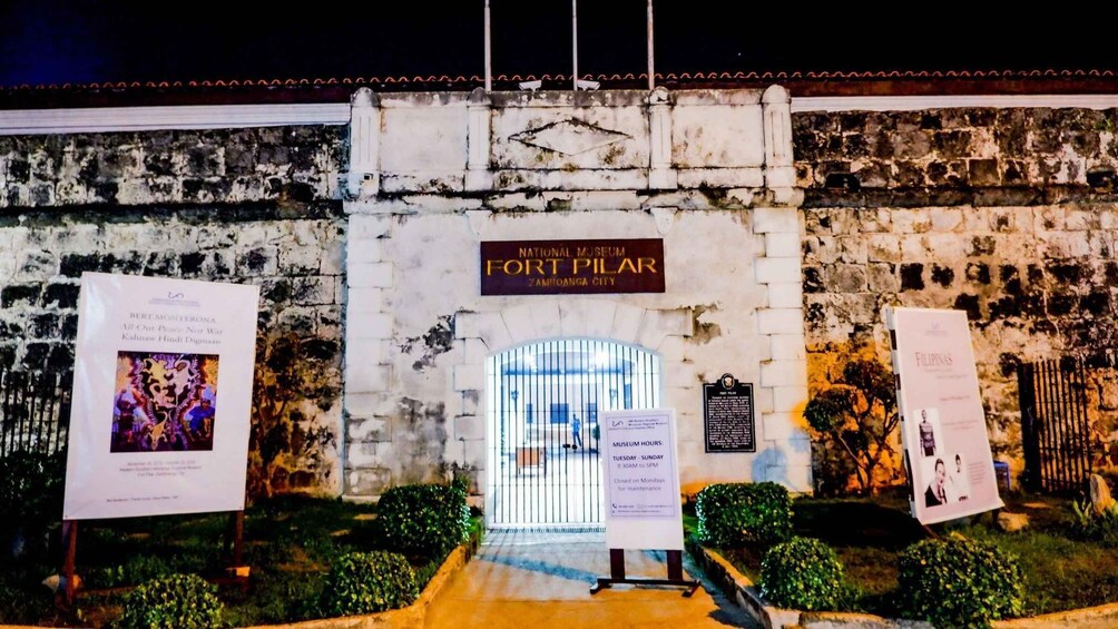 The entrance to the National Museum of Fort Pilar in Zamboanga City, with informational signs and a well-lit pathway. 2